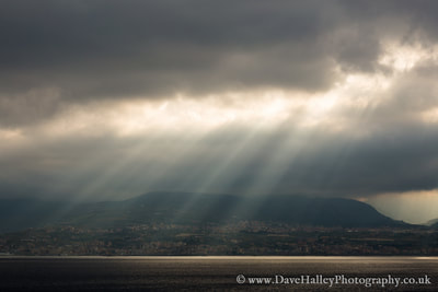 Photograph of sunlight breaking through the clouds viewed from Messina, Sicily looking towards Villa San Giovanni & Campo Calabro on the "toe" of Italy.